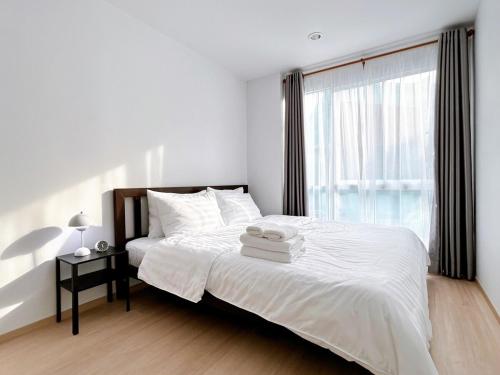 a bedroom with a white bed with a window at Wonderful Stay BTS Ratchayothin in Bangkok