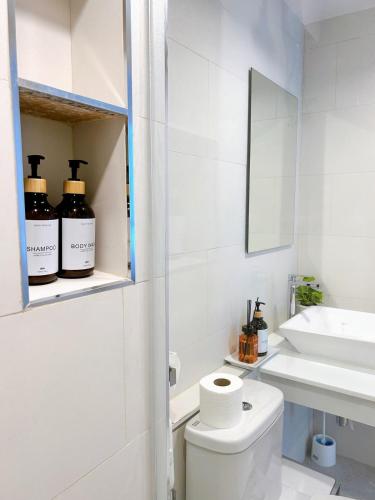 a white bathroom with a toilet and a sink at Wonderful Stay BTS Ratchayothin in Bangkok