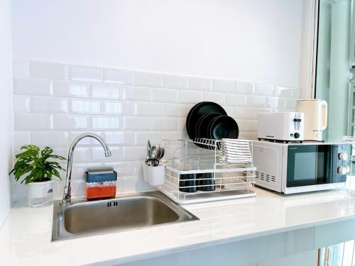 eine Küchentheke mit Spüle und Mikrowelle in der Unterkunft Wonderful Stay BTS Ratchayothin in Bangkok