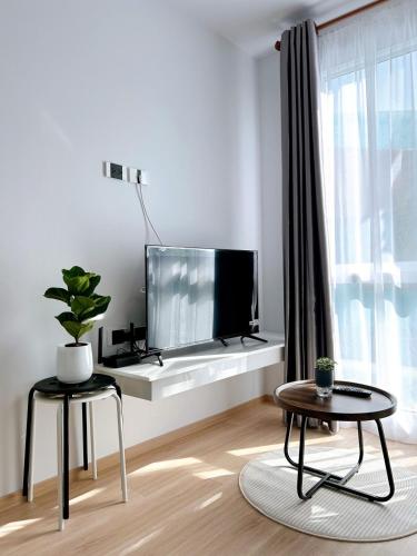 a living room with a flat screen tv and two tables at Wonderful Stay BTS Ratchayothin in Bangkok