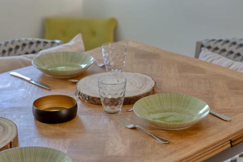 une table en bois avec des bols et des assiettes verts dans l'établissement La Kase Dali jolie maison de ville avec jardin, à Grand-Couronne