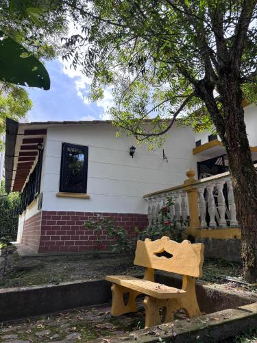 a wooden bench in front of a house at El susurro del agua casa blanca exclusiva natural in Ibagué