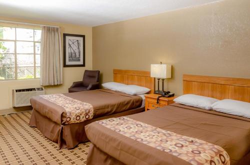 a hotel room with two beds and a chair at Relax Inn - Bryson City in Bryson City