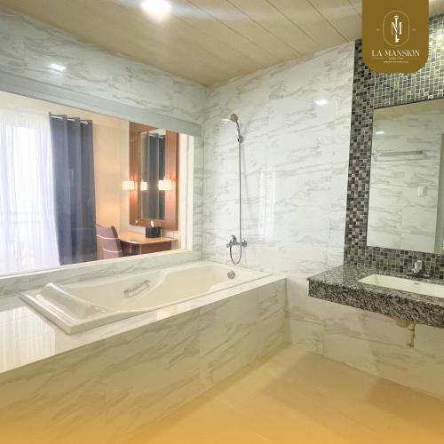 a white bathroom with a tub and a sink at La Mansion Tagaytay in Galicias