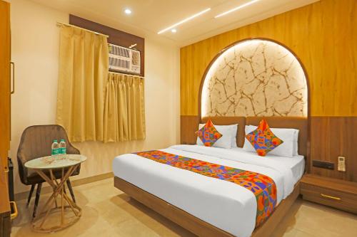 a bedroom with a bed and a table and a window at FabHotel Mishika Inn Near New Delhi Railway Station in New Delhi