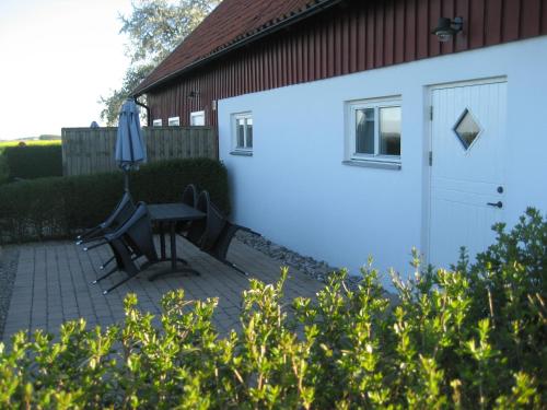 a patio with a table and an umbrella next to a building at Gårdsboende in Skårby