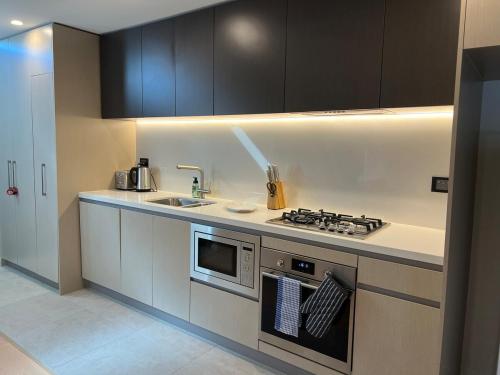 a kitchen with a stove top oven next to a sink at Modern Stay by Tallawong Metro in Riverstone