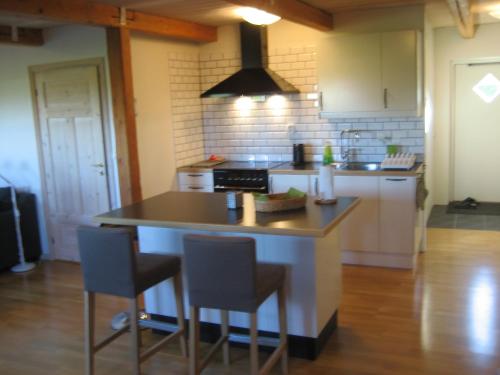 a kitchen with a island with two bar stools at Gårdsboende in Skårby