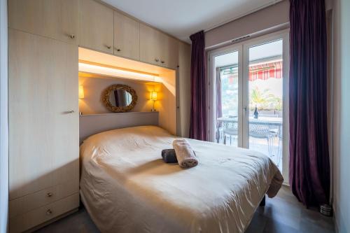 une chambre avec un lit et une grande fenêtre dans l'établissement Cannes plage - avec terrasse, vue, mer, piscine, plage, garage, à Cannes