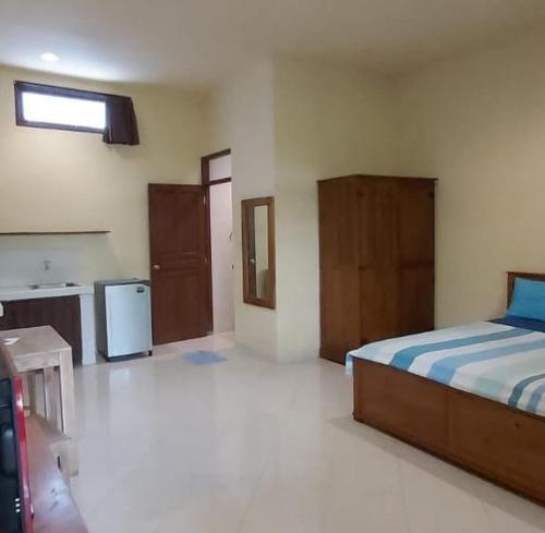 a bedroom with a bed and a sink and a refrigerator at Rach APT in Kerobokan