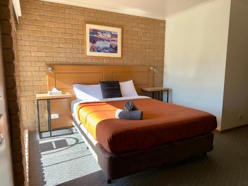 a bedroom with a large bed with a brick wall at Darling Junction Motor Inn in Wentworth
