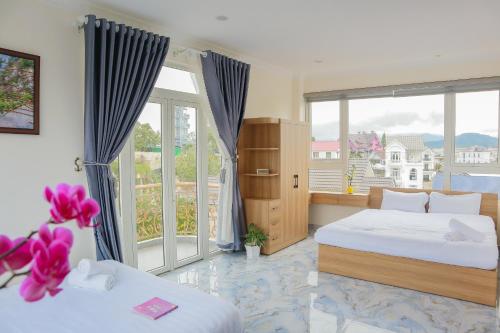 a bedroom with two beds and a large window at Hamia - Minh Anh Boutique Hotel in Da Lat