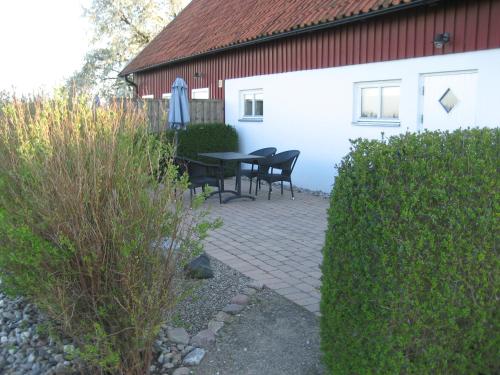 a patio with a table and chairs next to a building at Gårdsboende in Skårby