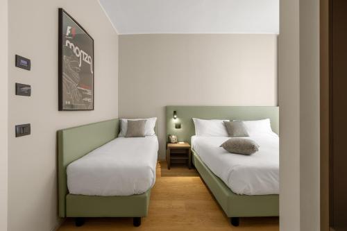 a bedroom with two beds and a chair at Energy Park Hotel in Vimercate