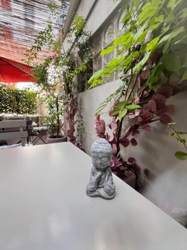 a small statue sitting on a white table with plants at Hôtel Eden - La Baigneuse in Juan-les-Pins