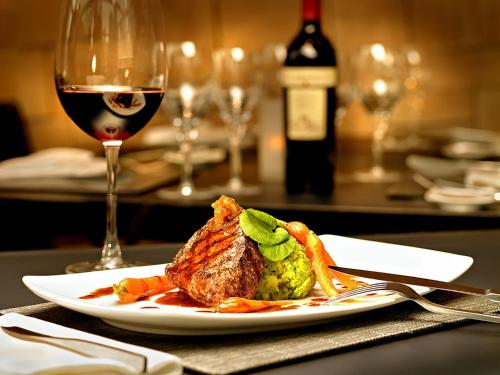 a plate of food on a table with a glass of wine at Studio De Luxe with Jacuzzi in Sumy