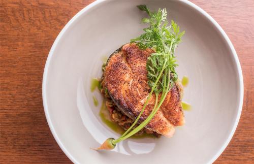 a white plate with a piece of fish with arig of herbs at Hyatt Regency Chicago in Chicago