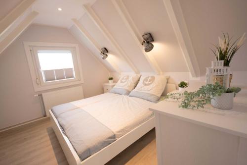 a bedroom with a white bed with a window at Ferienhaus Lüttje Strandhuus in Horumersiel
