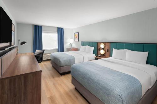 a hotel room with two beds and a flat screen tv at Wingate by Wyndham Augusta I-20 in Augusta