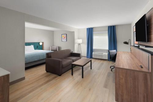 a hotel room with a bed and a couch and a television at Wingate by Wyndham Augusta I-20 in Augusta