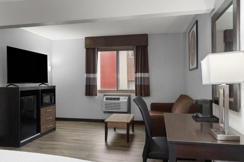 a hotel room with a desk and a living room at Ramada by Wyndham Cedar Rapids South in Cedar Rapids