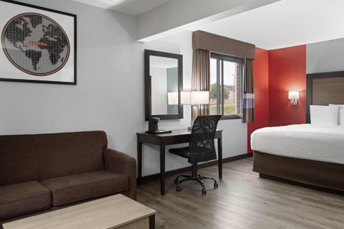 a hotel room with a bed and a desk and a bed and a couch at Ramada by Wyndham Cedar Rapids South in Cedar Rapids