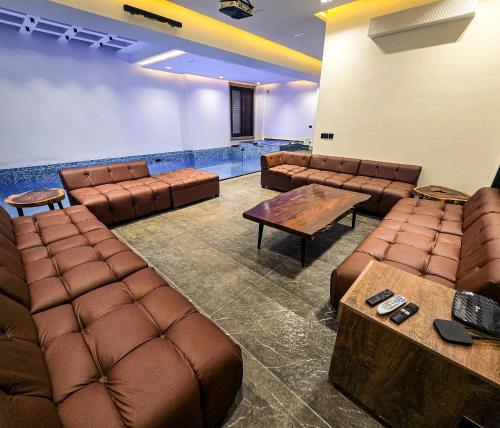 a waiting room with brown leather chairs and a pool at The White Suites in Karachi