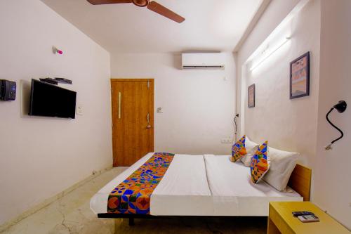a bedroom with a bed and a tv on the wall at FabHotel Sai Raj - Nr Zeel College in Pune