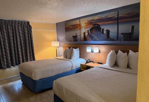 a hotel room with two beds and a painting on the wall at Days Inn by Wyndham St. Petersburg / Tampa Bay Area in St Petersburg