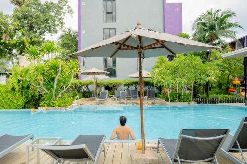 a man sitting in a swimming pool with an umbrella at Holiday Inn Express Phuket Patong Beach Central by IHG in Patong Beach