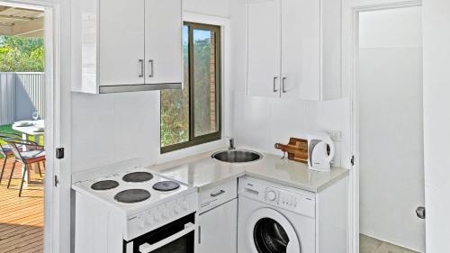 a white kitchen with a washing machine and a sink at Seashore Villa by Experience Jervis Bay in Vincentia