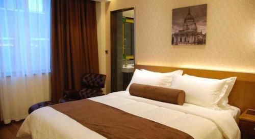 a hotel room with a large bed and a chair at James Joyce Coffetel Xian Big Goose Pagoda Tang Paradise Branch in Xi'an