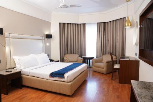a hotel room with a bed and a chair at Katriya Hotel and Tower in Hyderabad