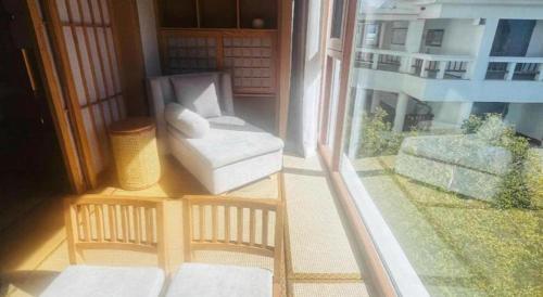 a balcony with a white chair and a window at Kunming Dianchi Garden Hotel & Spa in Kunming