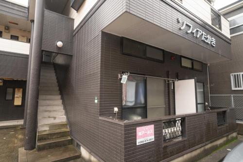 a black brick building with a sign on it at 貝塚GoodStay in Fukuoka