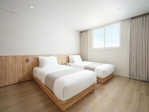 two beds in a hotel room with a window at Hanwha Resort Gyeongju in Gyeongju