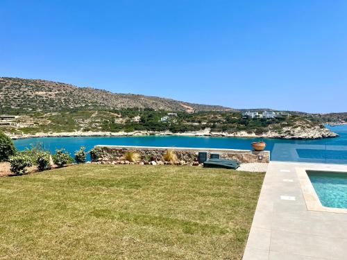 a yard with a swimming pool next to a body of water at SeaWave Villas, By Hellocrete in Chania Town