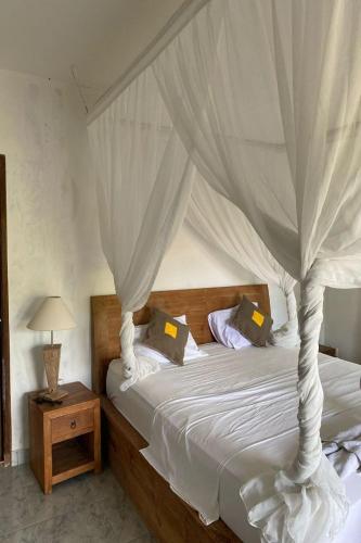 a bedroom with a white bed with a canopy at Budha House Ubud in Ubud