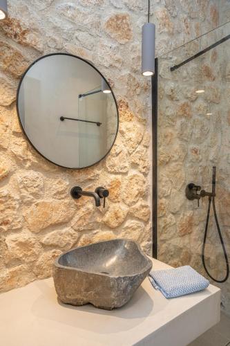 a bathroom with a stone sink and a mirror at Lithos Art Villas - Armonia in Lakíthra