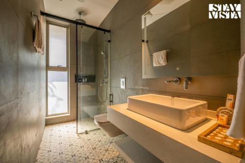 y baño con lavabo grande y ducha. en StayVista at Casa Vida Zen with BBQ, Pool, WiFi, en Vagator