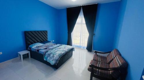 a blue bedroom with a bed and a chair at Shabiya homes in Abu Dhabi