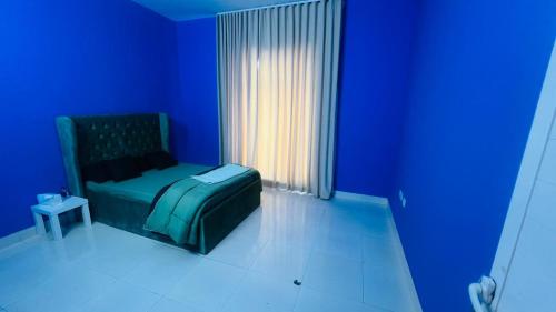 a blue room with a bed and a window at Shabiya homes in Abu Dhabi