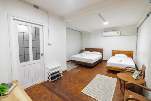 a room with two beds and a table and a door at Siam Breeze Inn - Self Check-in in Bangkok