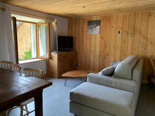 a living room with a couch and a tv at Les Astrances, logement dans une maison de village in LʼHuez