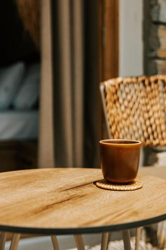 a brown cup sitting on a wooden table next to a chair at La Brise Luxury Suites in Néa Péramos