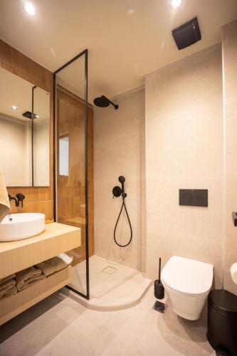 a bathroom with a shower and a toilet and a sink at La Brise Luxury Suites in Néa Péramos