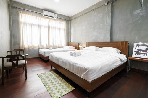 a bedroom with two beds and a table and a window at Siam Breeze Inn - Self Check-in in Bangkok