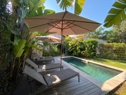 - une piscine avec 2 chaises et un parasol à côté dans l'établissement Sur les hauteurs de Cannes maison vue sur la baie, à Cannes