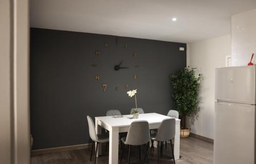 a dining room with a white table and a clock on a wall at Apartamentos Dacris in Jerte
