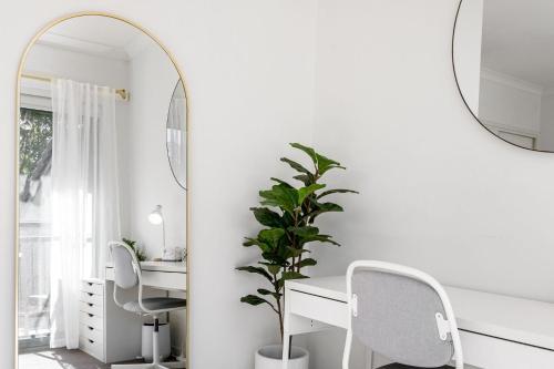 a room with a desk and two chairs and a mirror at Byron Beachside 2 in Byron Bay